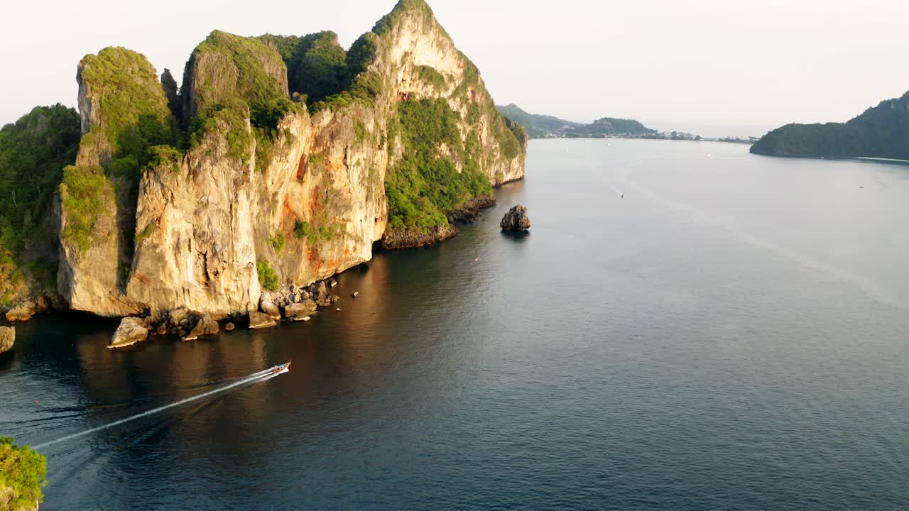 Sunset drone shot of Koh Phi Phi Don and Surrounding Islands with Nui Beach and Boats passing