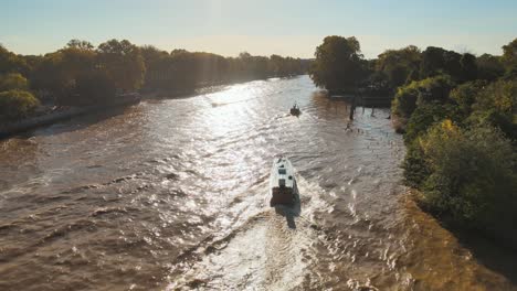 speedboat and wooden tourist boat sailing at lujan river on a sunny day in tigre, buenos aires, argentina