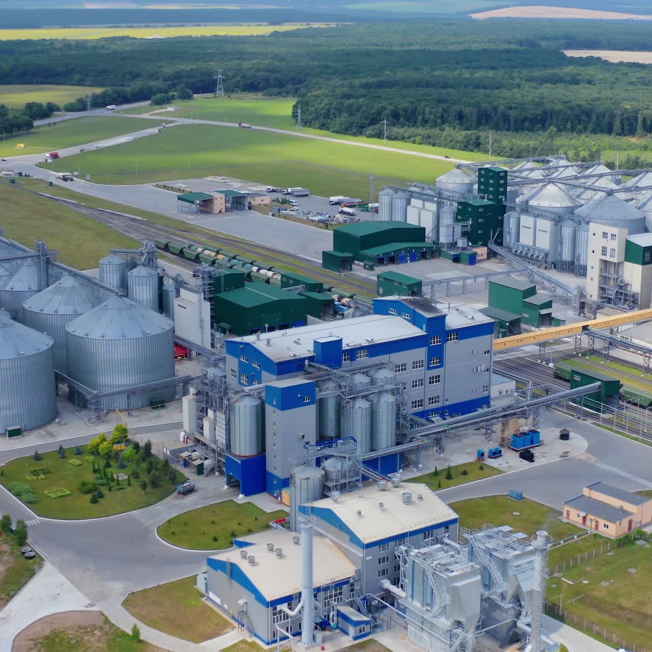 Contemporary factory on green nature background. Grain elevators for drying and storing crop. New industry on field. Aerial view
