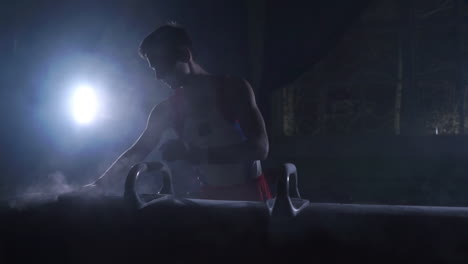 atleta gimnasta masculino realiza un handstand y un giro en un caballo de pommel sobre un fondo oscuro y humo en cámara lenta. programa olímpico. preparación para el ejercicio