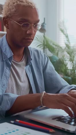 young focused african american man accountant typing email on laptop keyboard