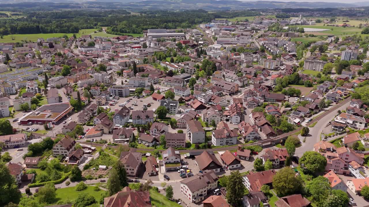 Swiss Buildings and houses of Hinwil in Summer season. Aerial top down shot. Red tile roofs of houses in idyllic small swiss district. Green forest trees in distance.