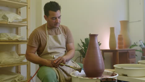 artesano masculino usando una antorcha de soplo calentando una escultura de vaso de arcilla en un taller de artesanos