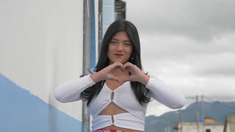 a beautiful latina girl folds her hands to form a love symbol on a rural road in the city of machachi, ecuador