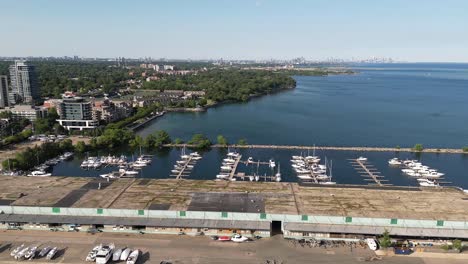 slow right to left shot of the parked boats by the water, seeing a lot of buildings of port credit, ontario, canada during the afternoon
