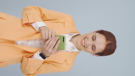 Vertical-video-of-Business-woman-texting-on-the-phone.-Happy-emoticon.