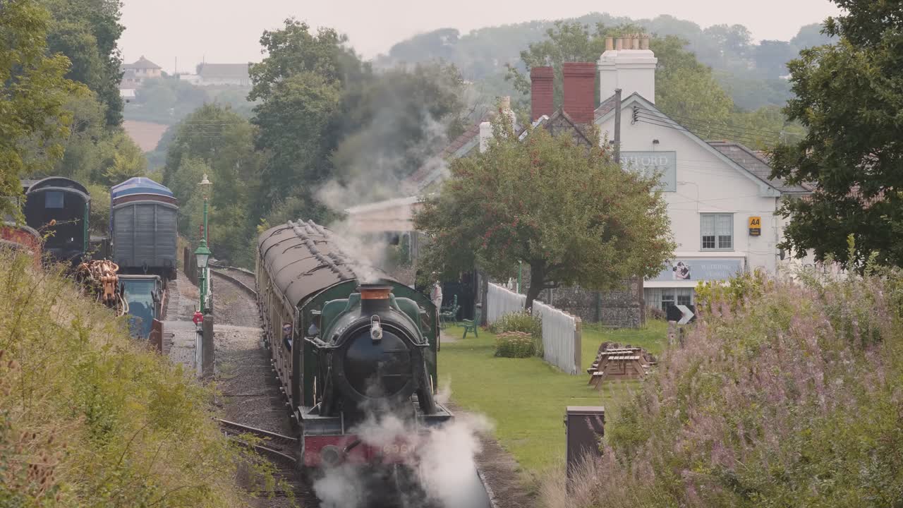 Touristic steam engine train leaving Washford Railway Station in Somerset, England