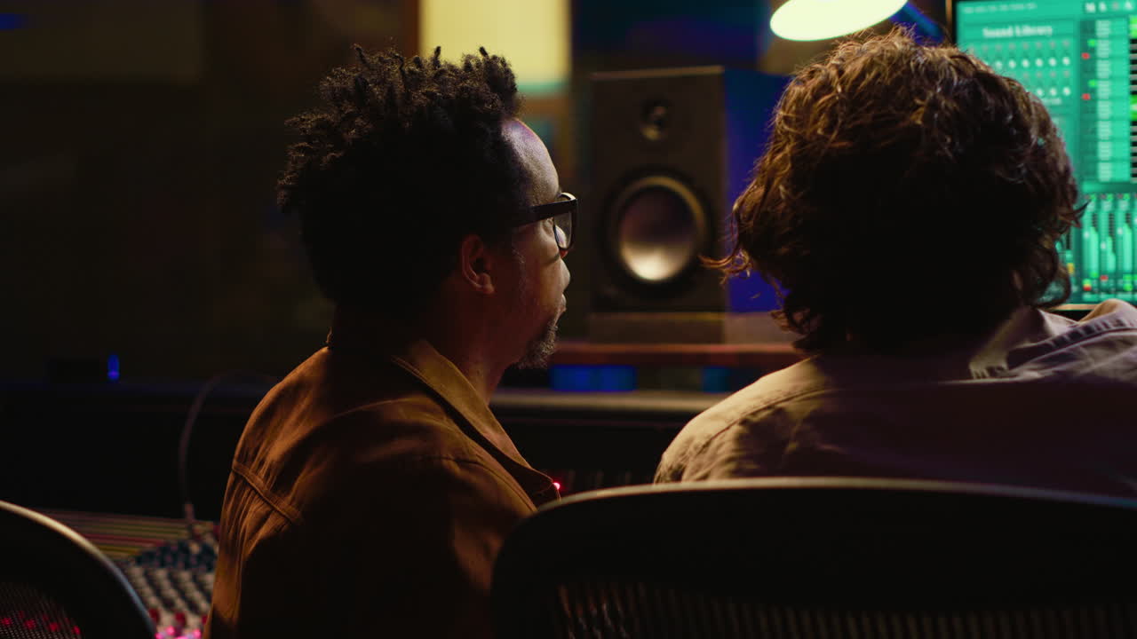 Musician and technician collaborating on mixing tracks to create successful hit