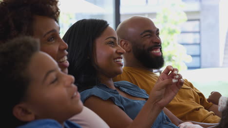 Eine-Afroamerikanische-Familie-Mit-Mehreren-Generationen-Entspannt-Sich-Zu-Hause,-Sitzt-Auf-Dem-Sofa-Und-Schaut-Gemeinsam-Fern