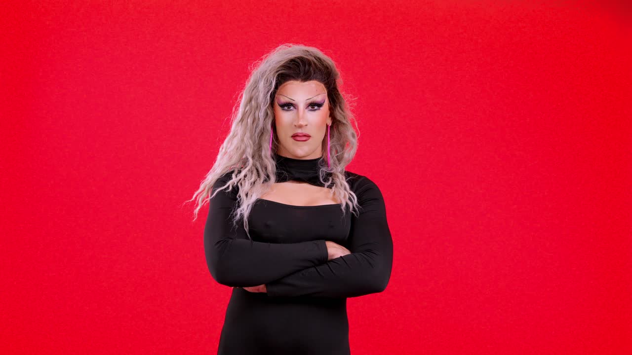 Drag queen sicura in posa su uno sfondo rosso vibrante