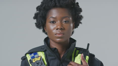 Studio-Portrait-Of-Serious-Young-Female-Police-Officer-Against-Plain-Background