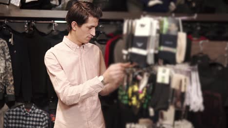 young man chooses socks for a gift in a clothing store