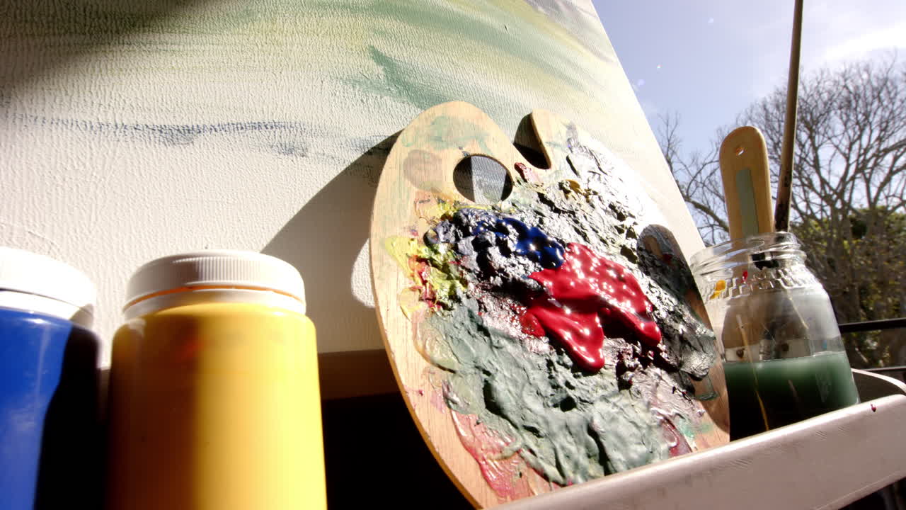 Colorful paint tubes rest beside well-used palette with vibrant smears
