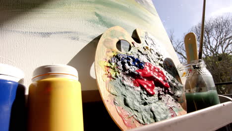 colorful paint tubes rest beside well-used palette with vibrant smears