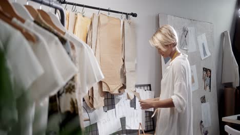 mujer sastre eligiendo piezas de ropa en el taller de costura