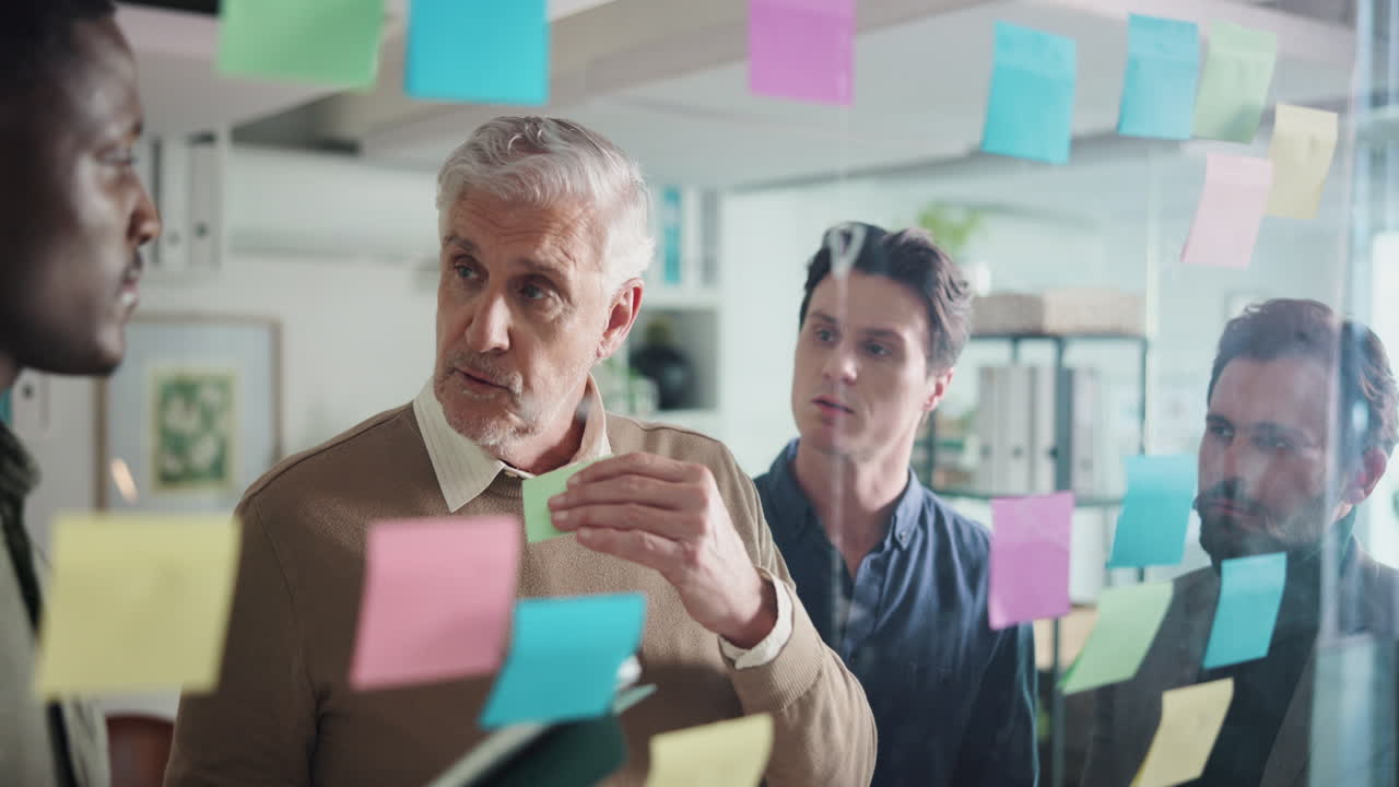 Diverse Team Brainstorming with Post-it Notes on Glass Wall