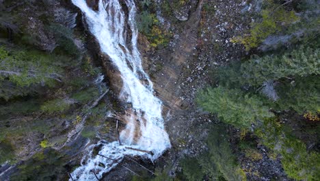 Imágenes-De-Drones-Verticales-Desde-Arriba-De-Una-Cascada-Que-Fluye-A-Través-De-Los-Bosques-De-Un-Parque-Nacional-En-Alberta,-Canadá