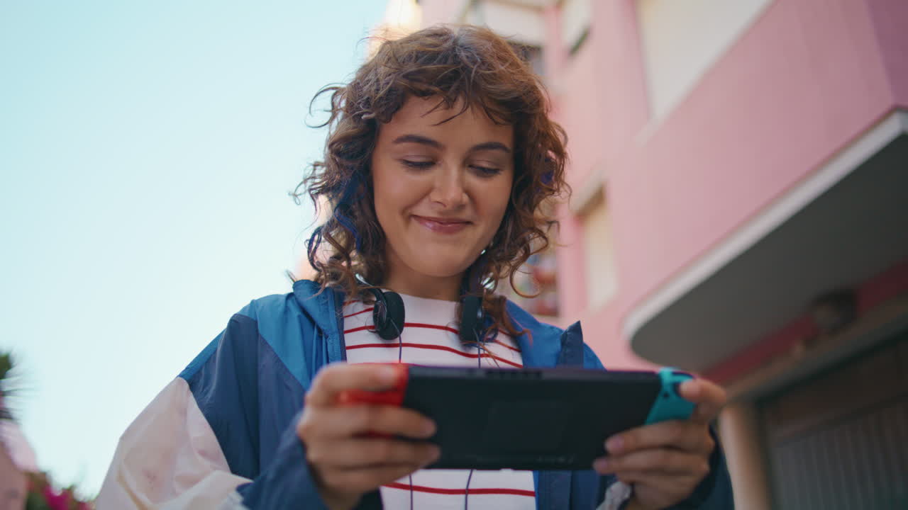 niña jugando a la consola portátil caminando por la calle de cerca. adolescente involucrado en videojuego