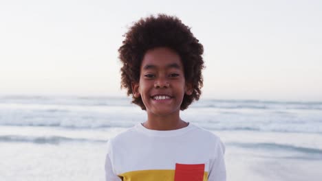 portrait of african american boy smiling while standing at the beach