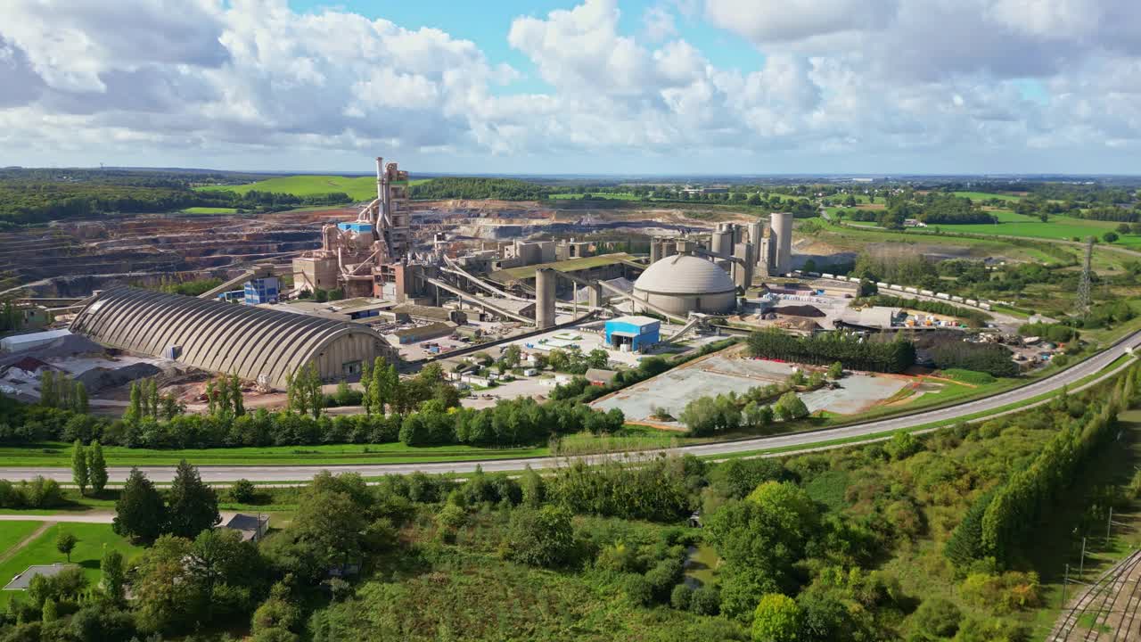 Aerial panoramic approach of industrial quarry cement plant with rural surroundings and hills in Saint Pierre la Cour