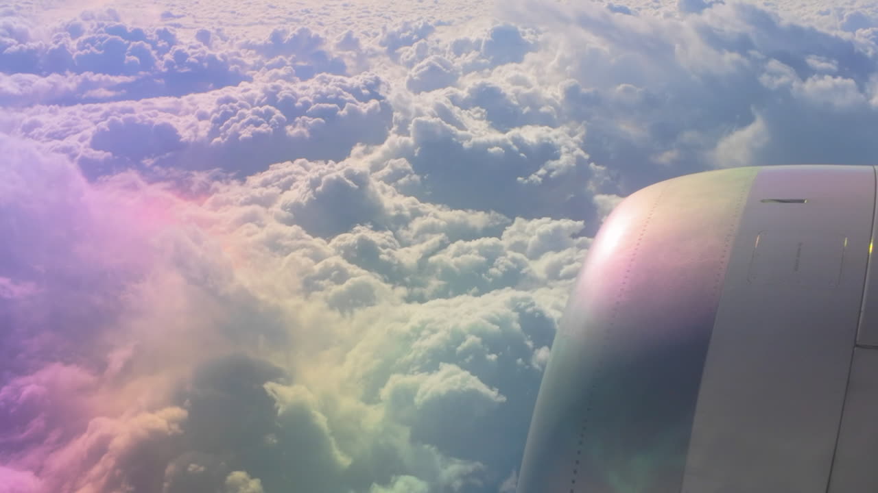 Close-up of an airplane engine with soft cloud formations in the background. The sunlight adds a reflective rainbow hue to the engine surface