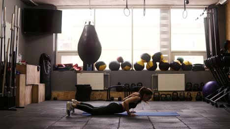 Chica-Morena-Atractiva-Y-Deportiva-Haciendo-Una-Serie-De-Ejercicios-Para-Quemar-Grasa-En-El-Gimnasio-Sobre-La-Alfombra-Del-Piso.-Fitness-Y-Atención-Sanitaria.