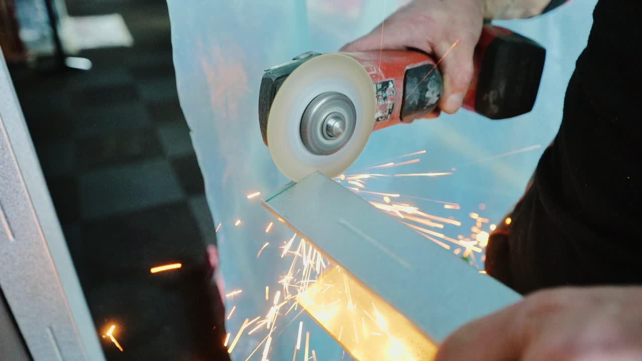 Expert worker slices metal profile barehanded in slow motion grinding sequence