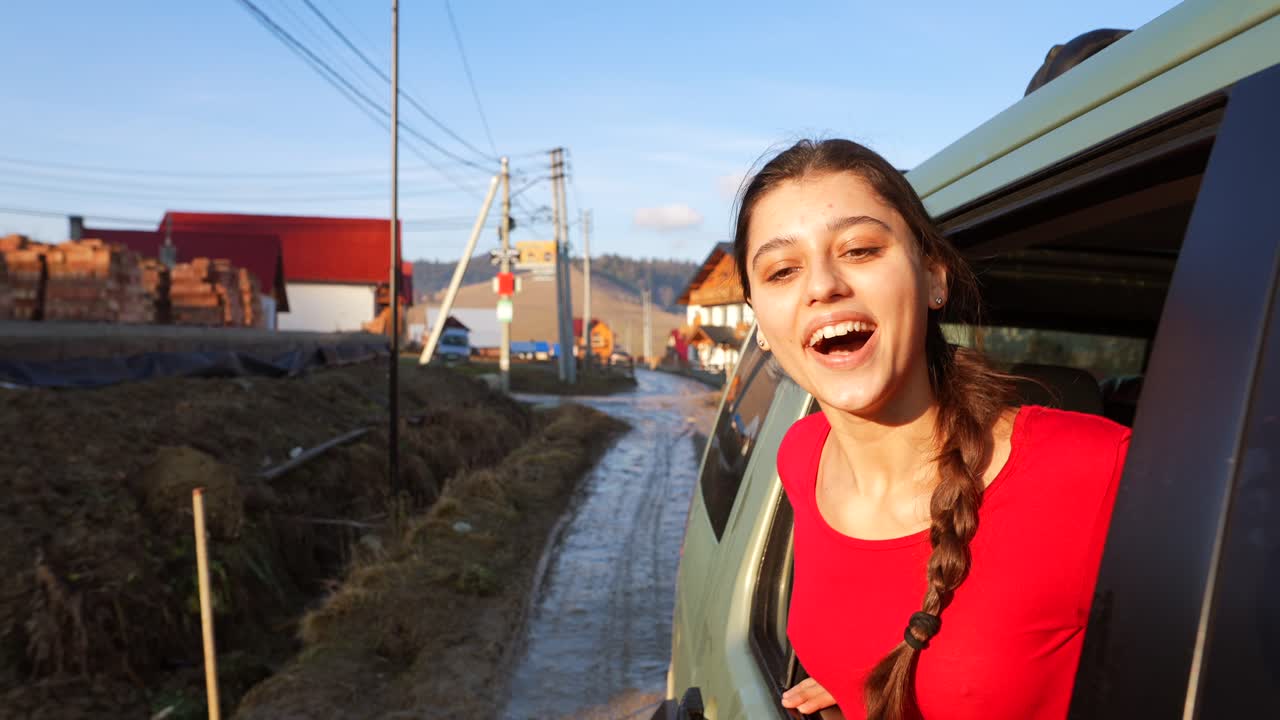 возбужденная женщина смотрит из окна машины на грунтовой дороге