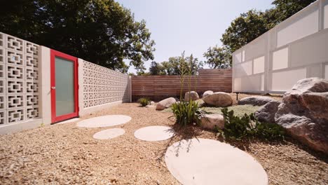 push in shot of a modern california inspired breeze block garden with a red door on the side of a luxury home