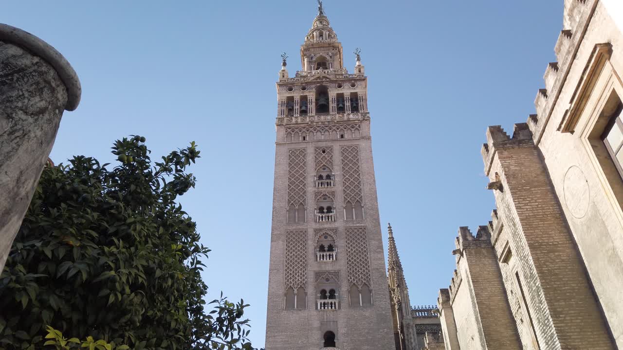 Lenta carrellata a destra, Torre campanaria della Giralda alla Cattedrale di Siviglia con cielo blu, Spagna.