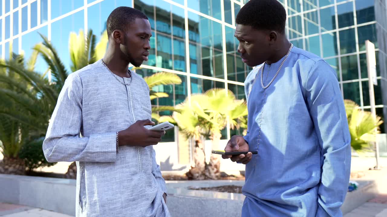 Two African men using cell phones in city