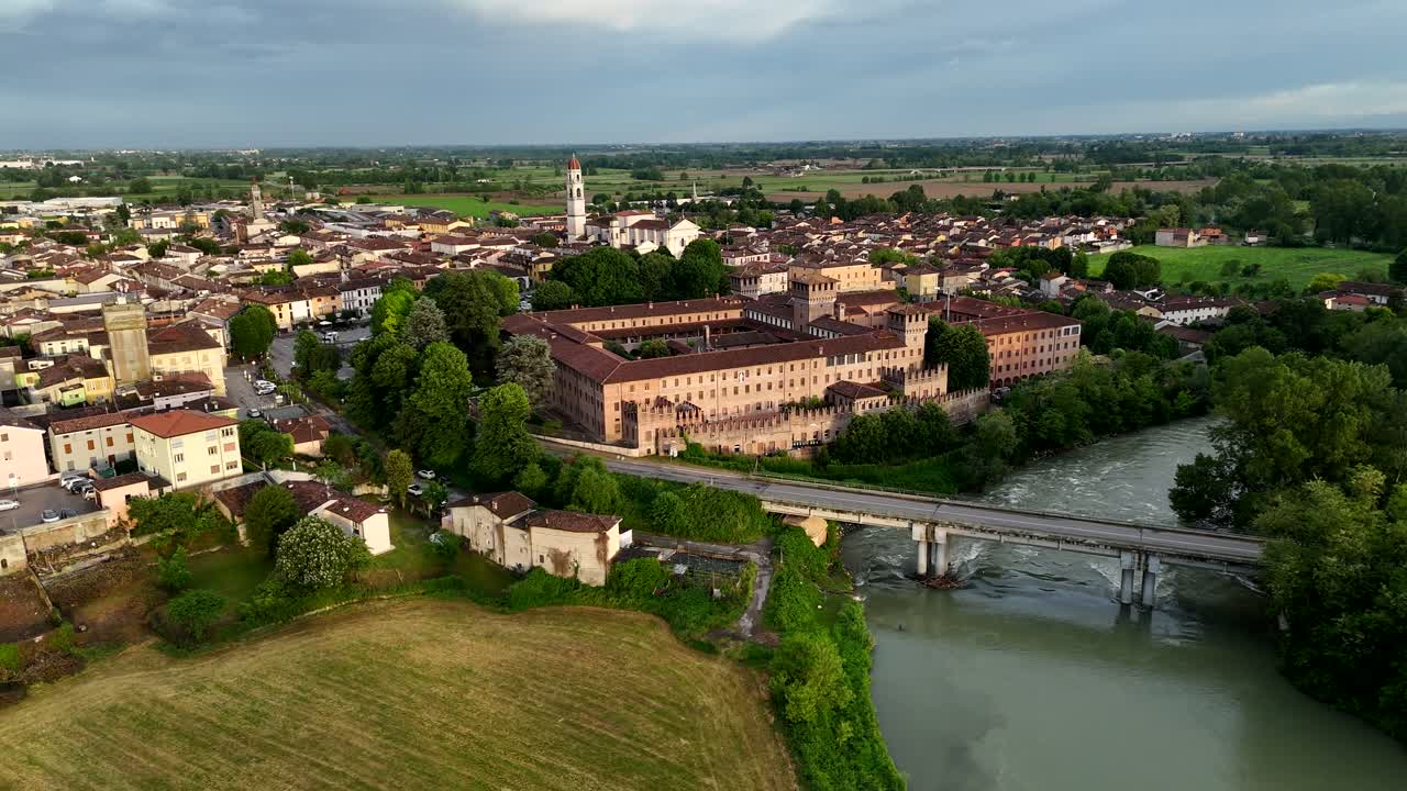 Aerial pull-out from Castello di Pontevico along the Oglio River, with the town’s historic center and countryside unfolding in the background