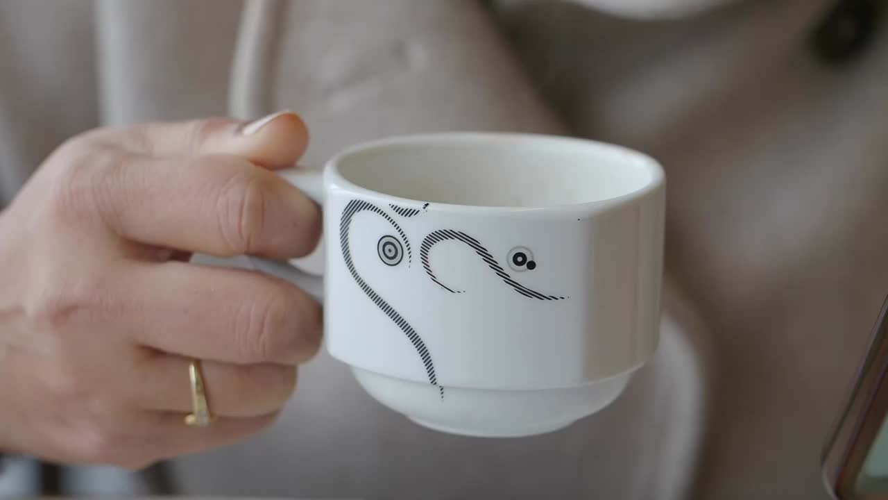 Primo piano di una mano che tiene una tazza di caffè bianca