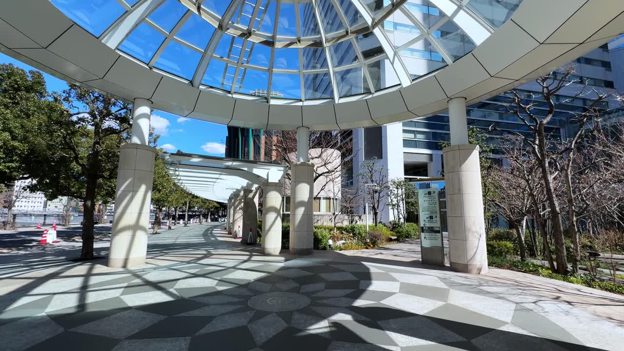 Glass-covered structure in a Tokyo street with trees and modern buildings in view