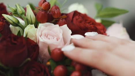 woman touches elegant fresh flowers of wedding bouquet