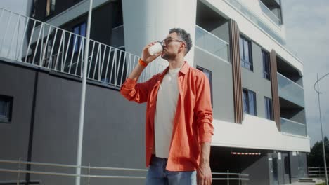 man drinking coffee outdoors near modern building