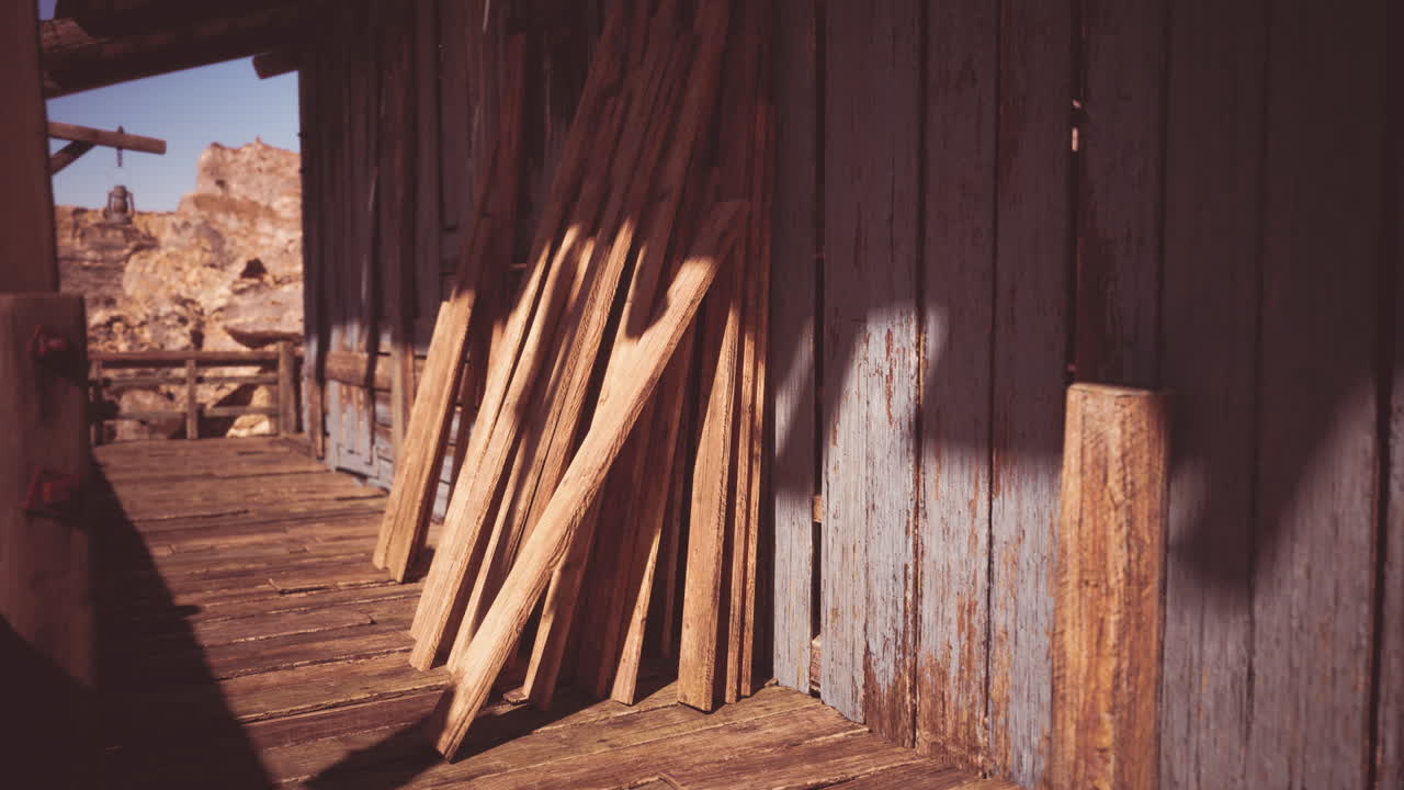 Wooden planks leaning against a rustic building in a sunlit desert landscape