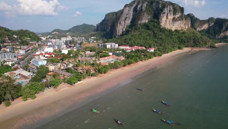 Barcos-Tailandeses-De-Cola-Larga-Anclados-En-El-Agua-De-La-Playa-De-Ao-Nang-En-Krabi-Tailandia-En-Un-Día-Soleado-De-Verano-Con-Grandes-Acantilados-De-Piedra-Caliza-En-La-Distancia