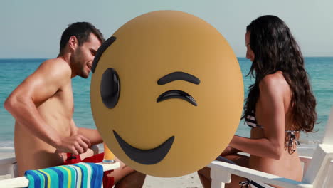 relaxing on beach, man and woman with large winking emoji animation overlay