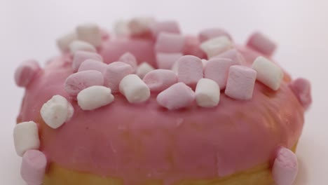 bright and colorful sprinkled donut close-up shot spinning on a white background. assortment of donuts of different flavors. pink glazed and sprinkles donut rotation