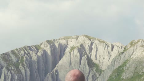 bald man contemplating mountain peaks