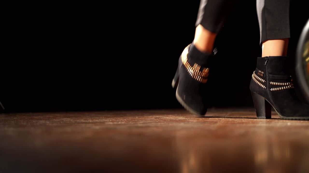 Female legs step back and pull the baby stroller. New modern baby pram in the darkness of the room. Dark backdrop.