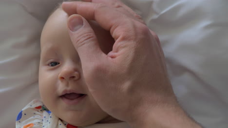 a closeup of a baby girl face and a father hand touching her