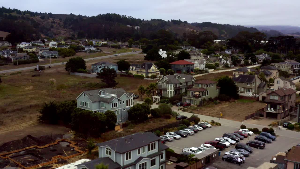 Aerial: Half Moon Bay Beach Cliffs, People Walking and Neighborhood. Flying Forward