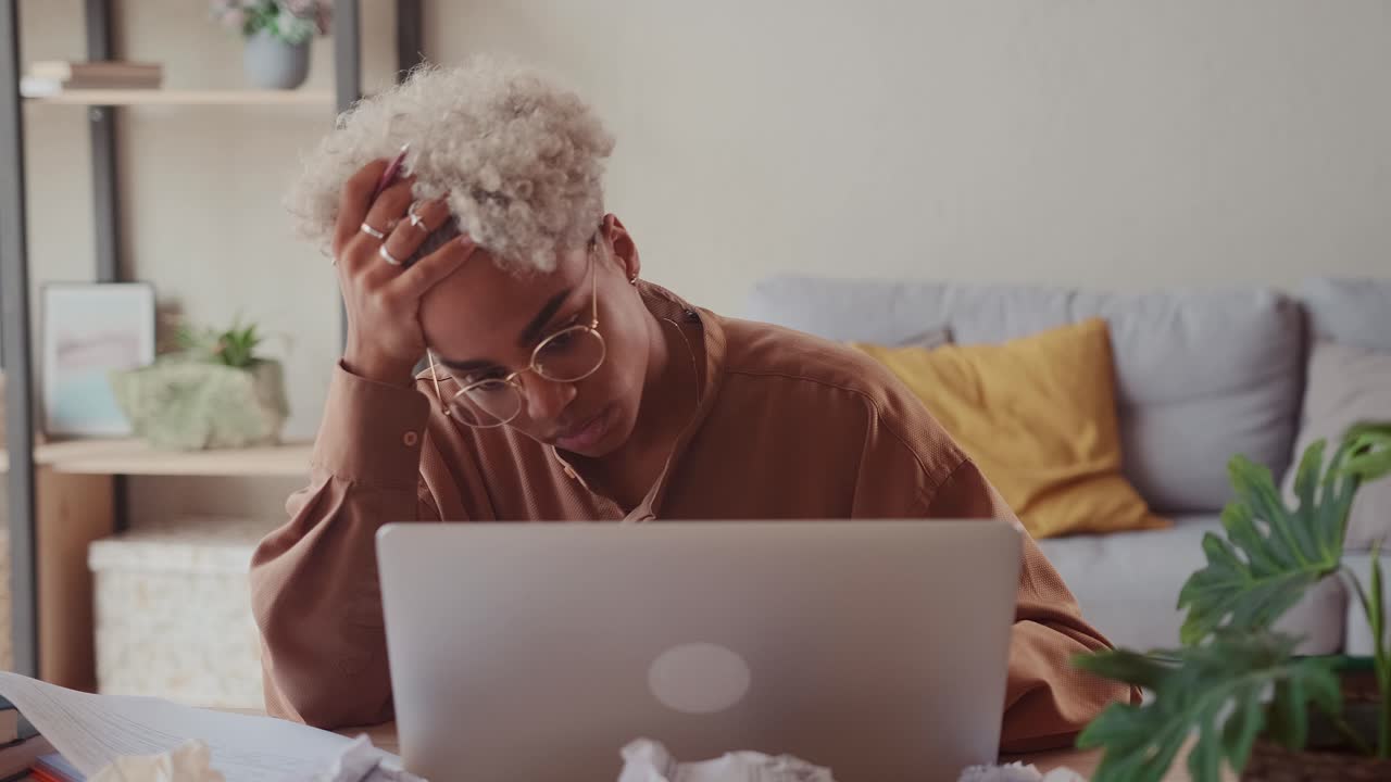 Woman at laptop with crumpled paper feeling hopeless of doing difficult task
