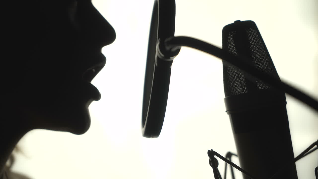 Silhouette of a woman singing a song in a recording studio. Black and White.
