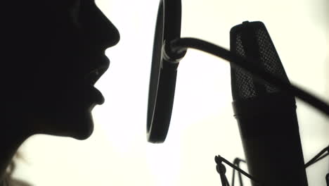 silhouette of a woman singing a song in a recording studio. black and white.