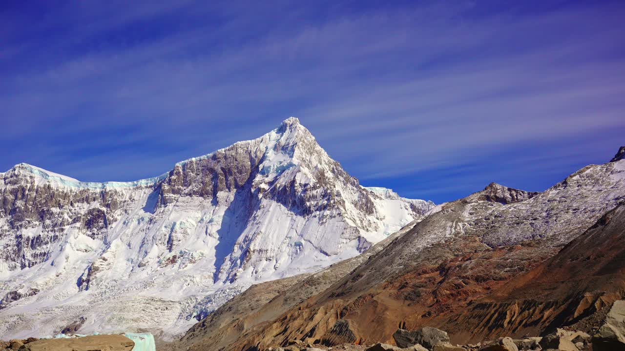 Time-lapse shot of Mount San Lorenzo's snow-covered peak rising above rugged slopes under a clear blue sky in the remote Perito Moreno National Park. Santa Cruz, Argentina