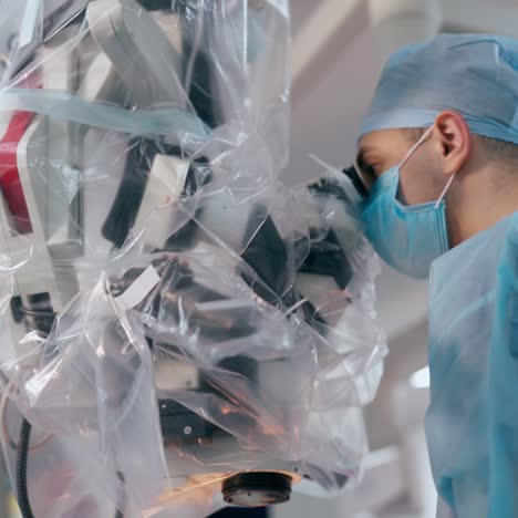 surgeon uses microscope during operation. medical specialist and a nurse in masks perform a surgery on modern equipment background. neurosurgery concept.