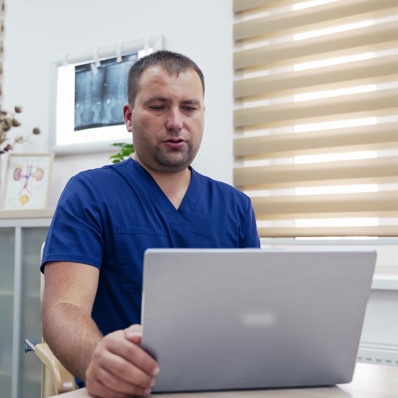 Telemedicine. Medical specialist sitting at his desk and consulting patient via video call in office. Male therapist using laptop during remote consultation.